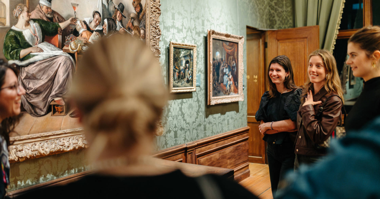 Een groep mensen bekijkt een schilderij in een museum.