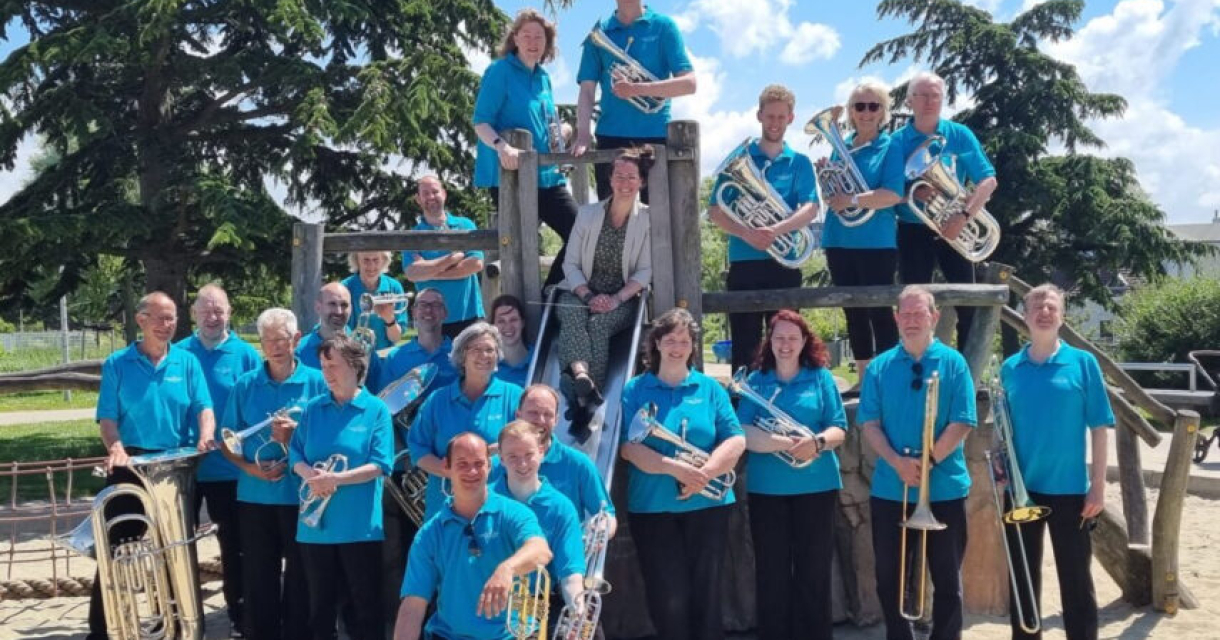 Een blazersensemble gekleed in blauwe shirts poseert in een speeltuin.