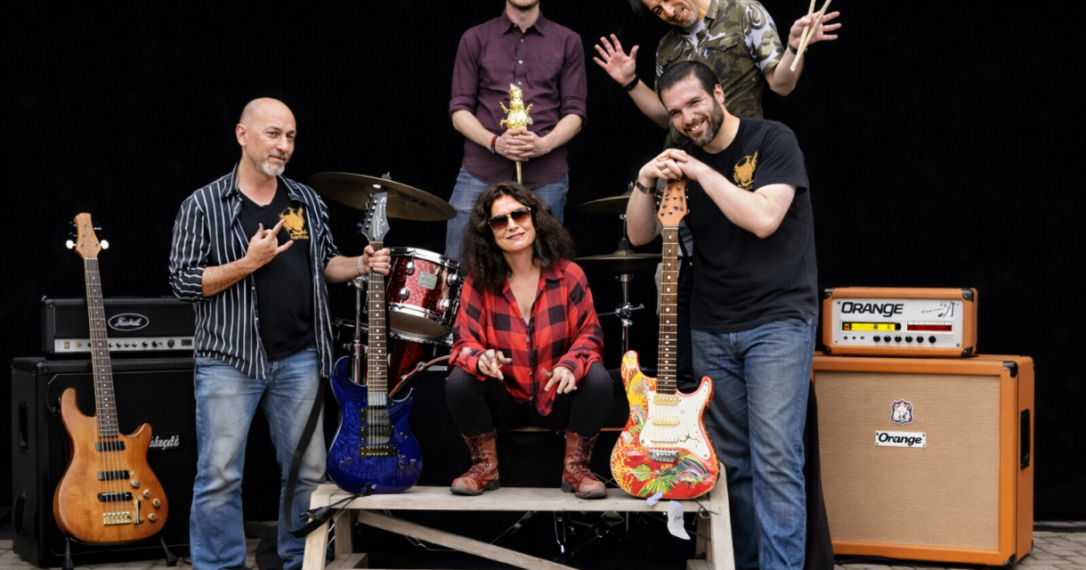 Een band met vijf leden poseert met gitaren en drums.