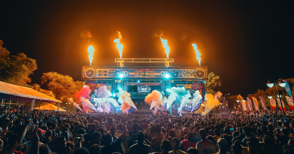 Een menigte geniet van een festival met lichtshows en vuurwerk.