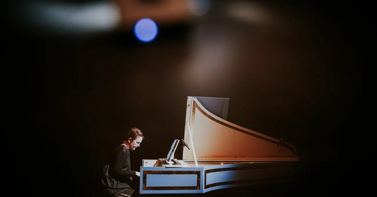 A pianist playing a grand piano in the dark.