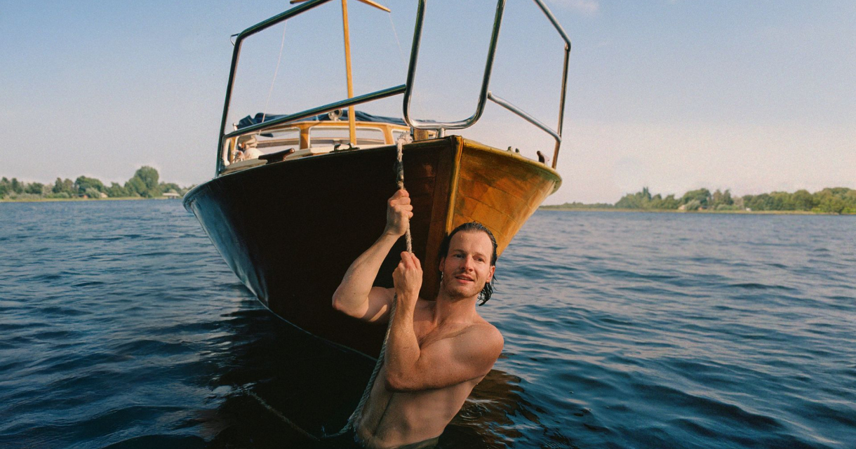 Een man hangt aan een touw terwijl hij in het water staat.