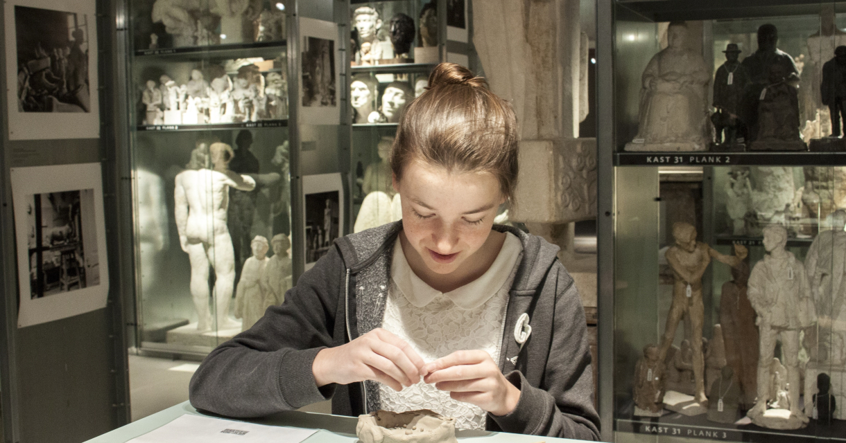 Een meisje werkt met klei in een museum.