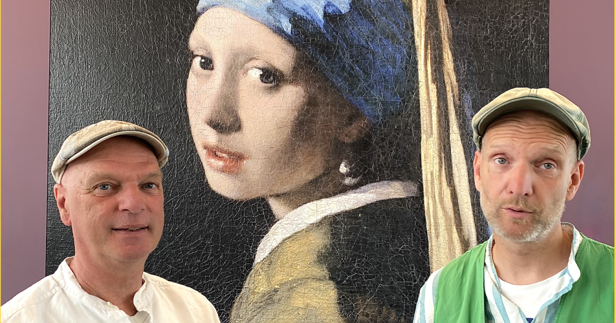Twee mannen met pet poseren voor een groot kunstwerk van Vermeers Meisje met de parel