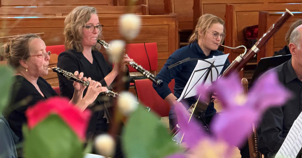 Drie muzikanten spelen blaasinstrumenten in een kerk.