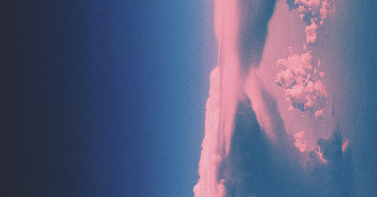 Roze wolken in verticale vorming tegen een diepblauwe lucht