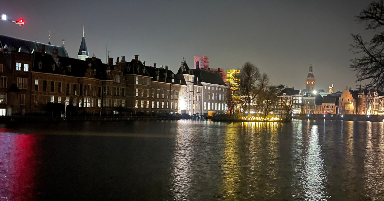 Een verlichte Hofvijver met historische gebouwen bij nacht.