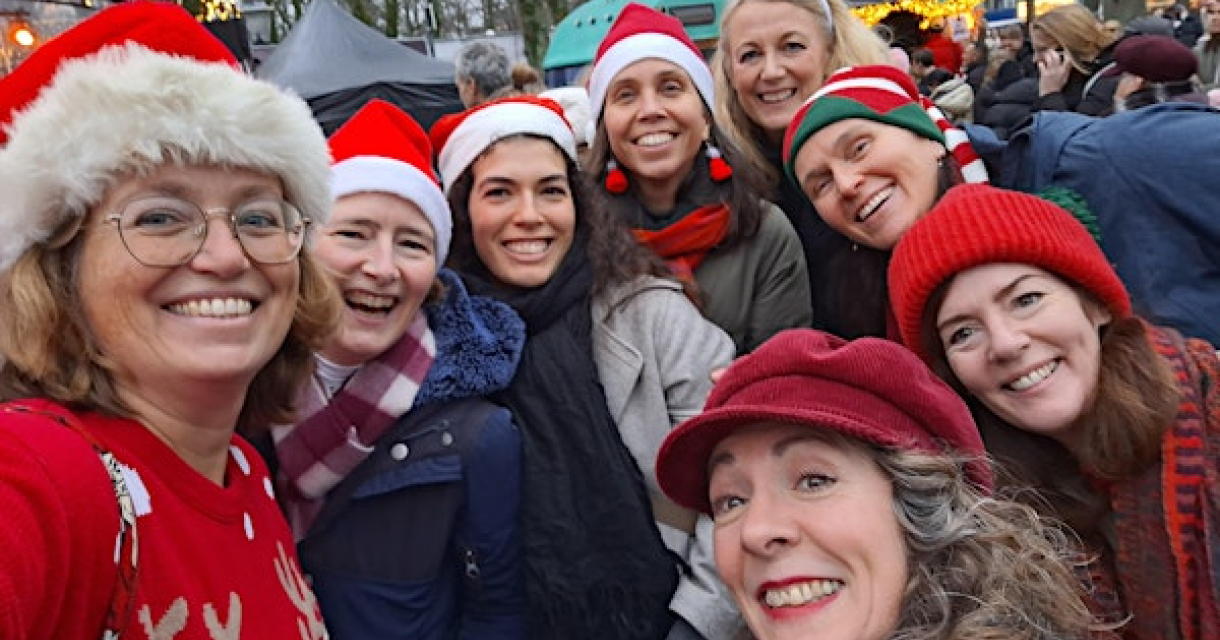 Group of women with Christmas accessories posing happily.