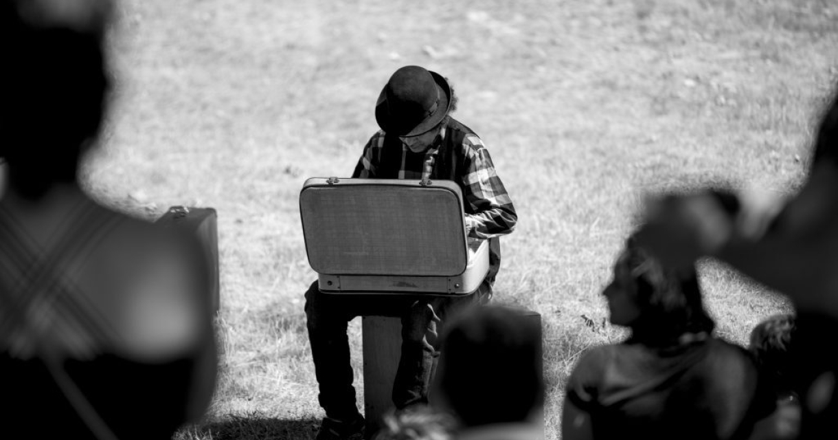Een muzikant in een zwart-wit foto speelt muziek op een koffer.
