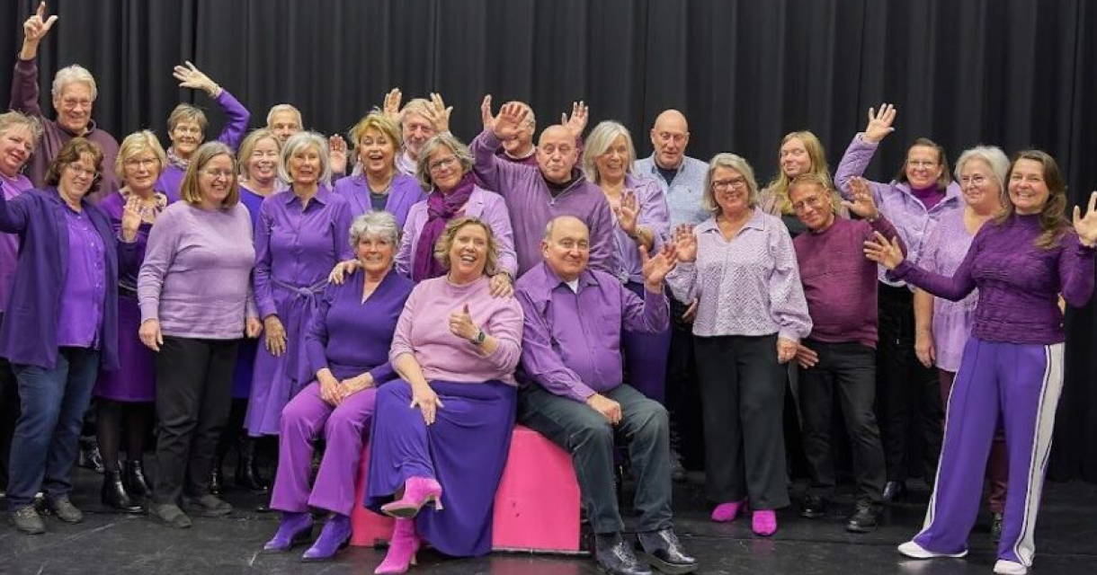 Een groep mensen in paarse kleding met handen in de lucht.