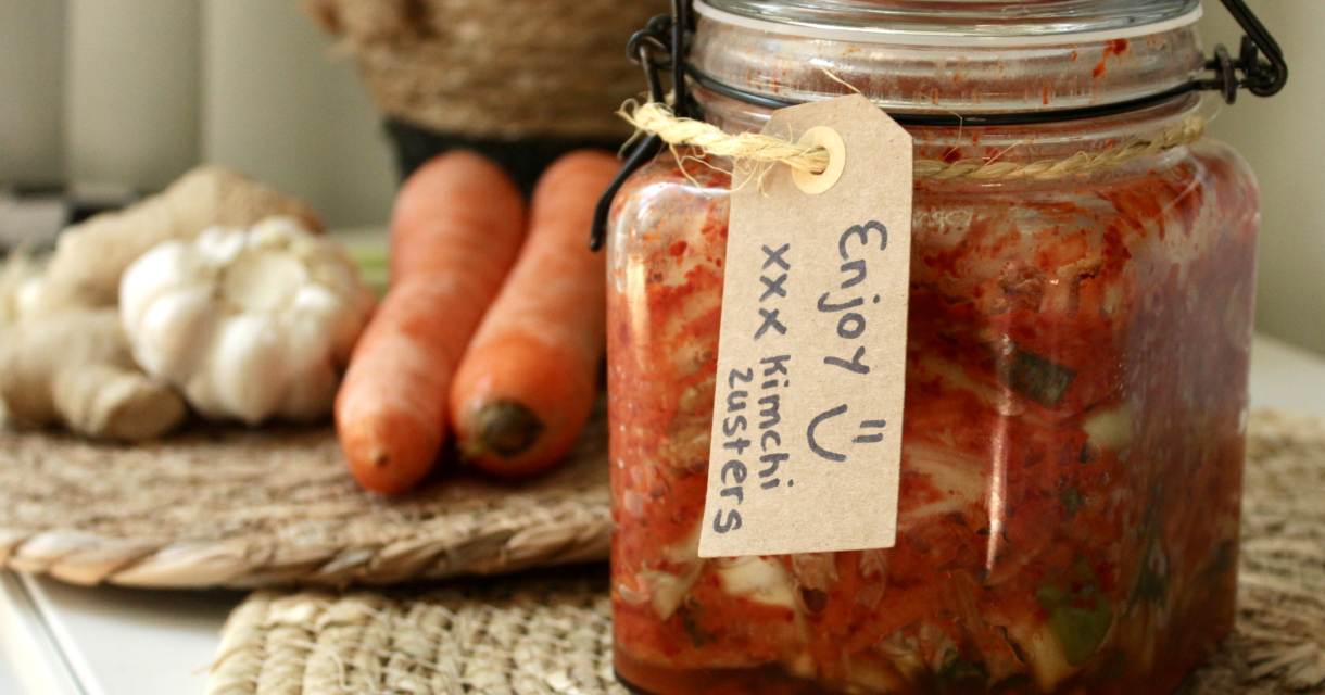 Weckpot met kimchi op een gevlochten placemat, met knoflook en wortels op de achtergrond Weckpot met kimchi op een gevlochten placemat, met knoflook en wortels op de achtergrond