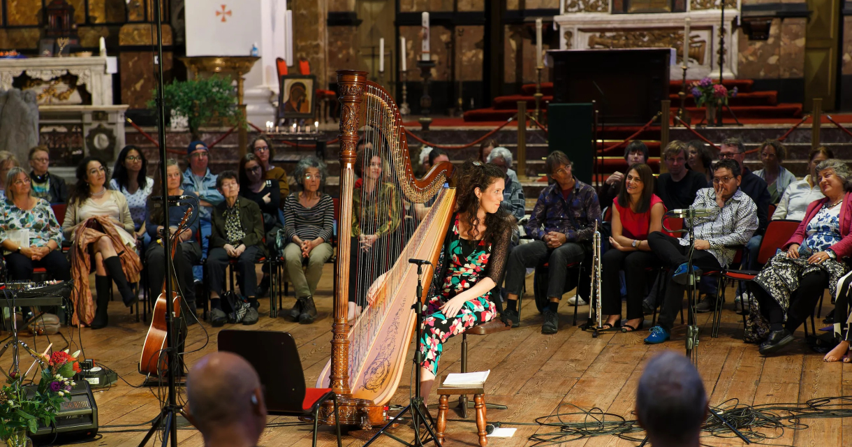 A harpist performs for an audience in a concert hall.