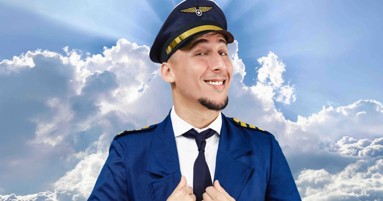 Een vrolijke vluchtkapitein in uniform met een blauw pak en pet, tegen een achtergrond van wolken.