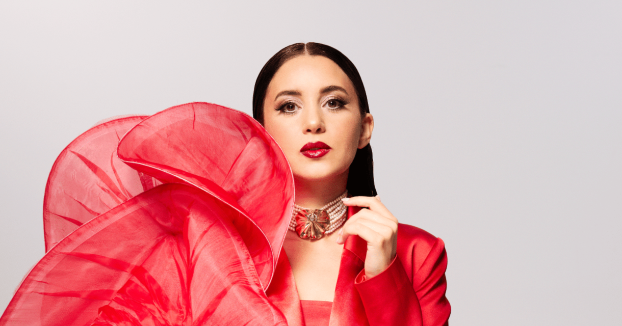 Model met een grote rode bloem en glamourous uitstraling.