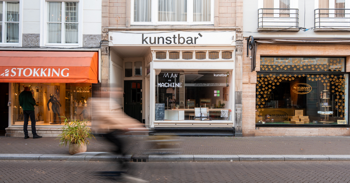 Een drukke straat met winkels en een fietser die passeert.