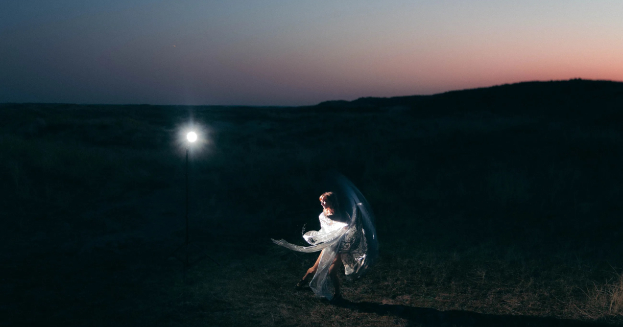 Een vrouw danst met een doorzichtig doek in de schemering.