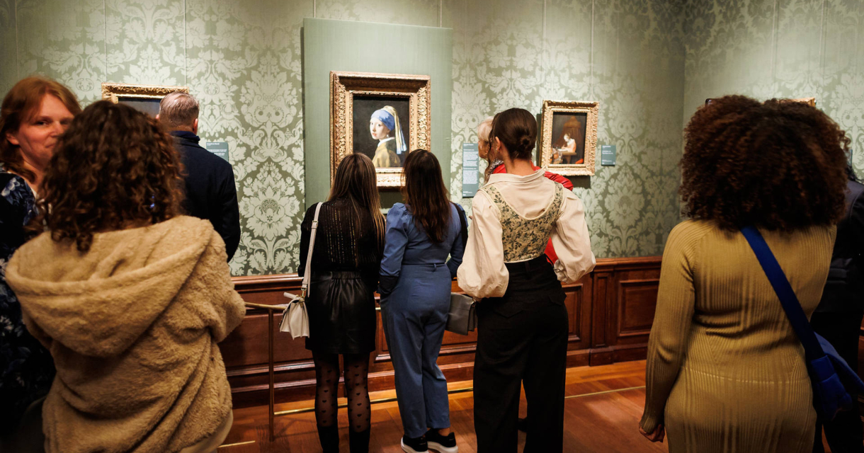 Mensen bekijken schilderijen in een museum.