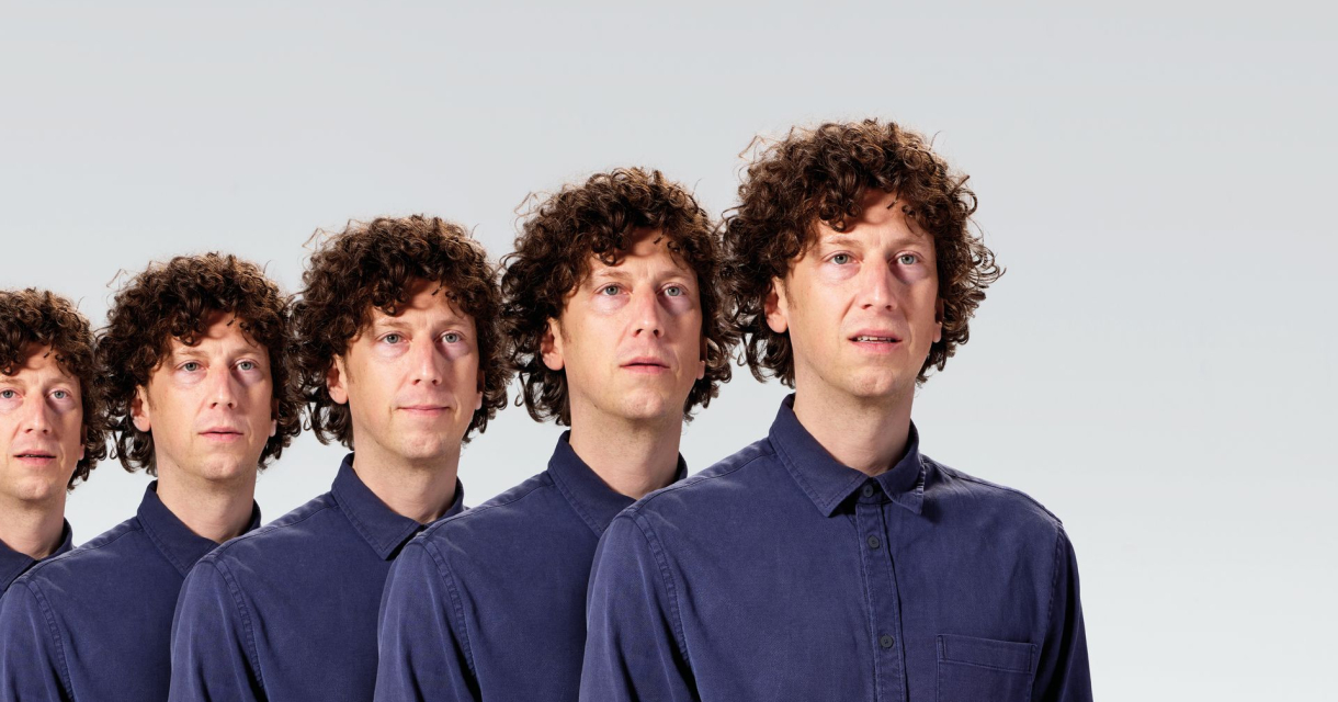 Vijf mannen met krullend haar staan naast elkaar.