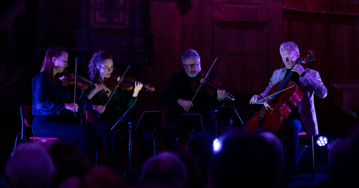 Vier muzikanten spelen een klassiek stuk op hun instrumenten.