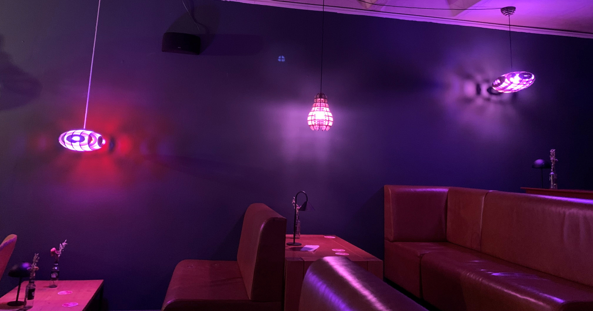 Een interieur met paarse, moderne lampen en leren banken.