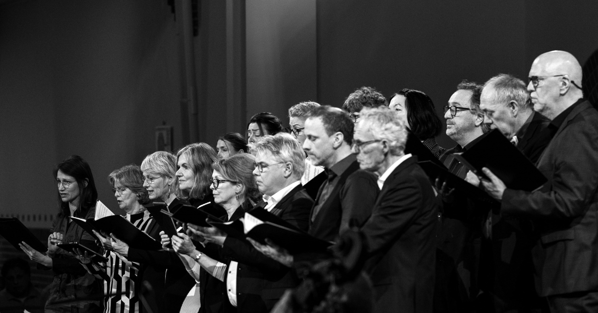 Een groep mensen zingt in een koor, met bladmuziek.