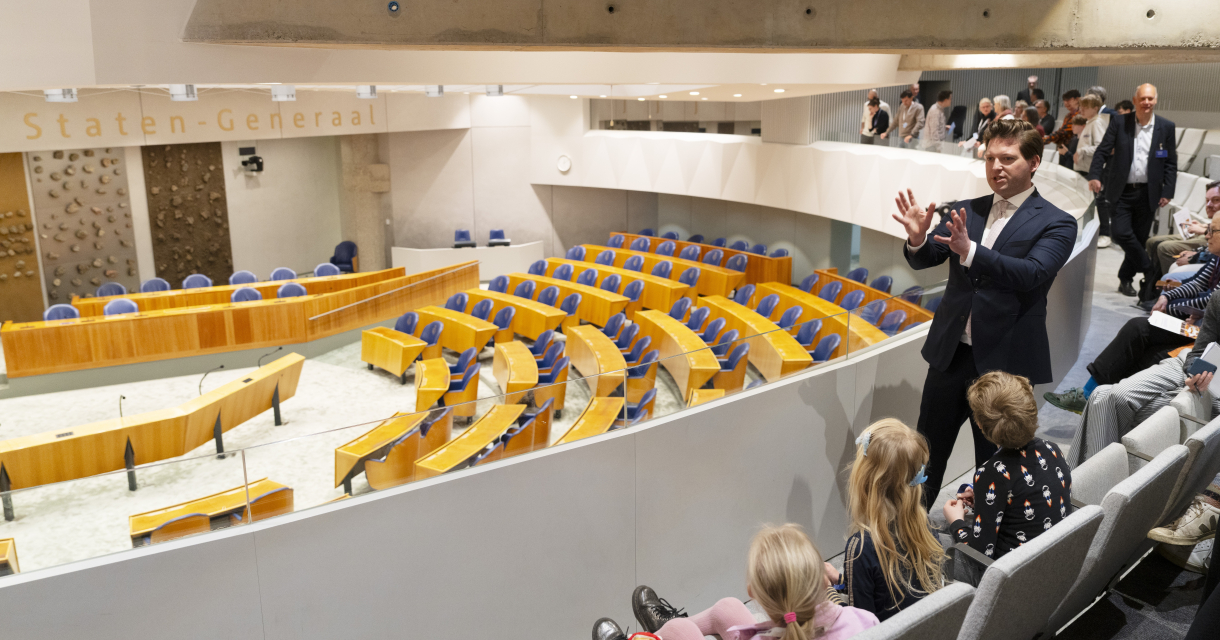 .Een gids legt dingen uit aan bezoekers in de Tweede Kamer.