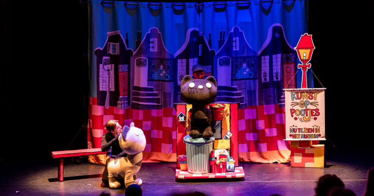Een poppenkastshow met een kind en twee grote knuffeldieren.