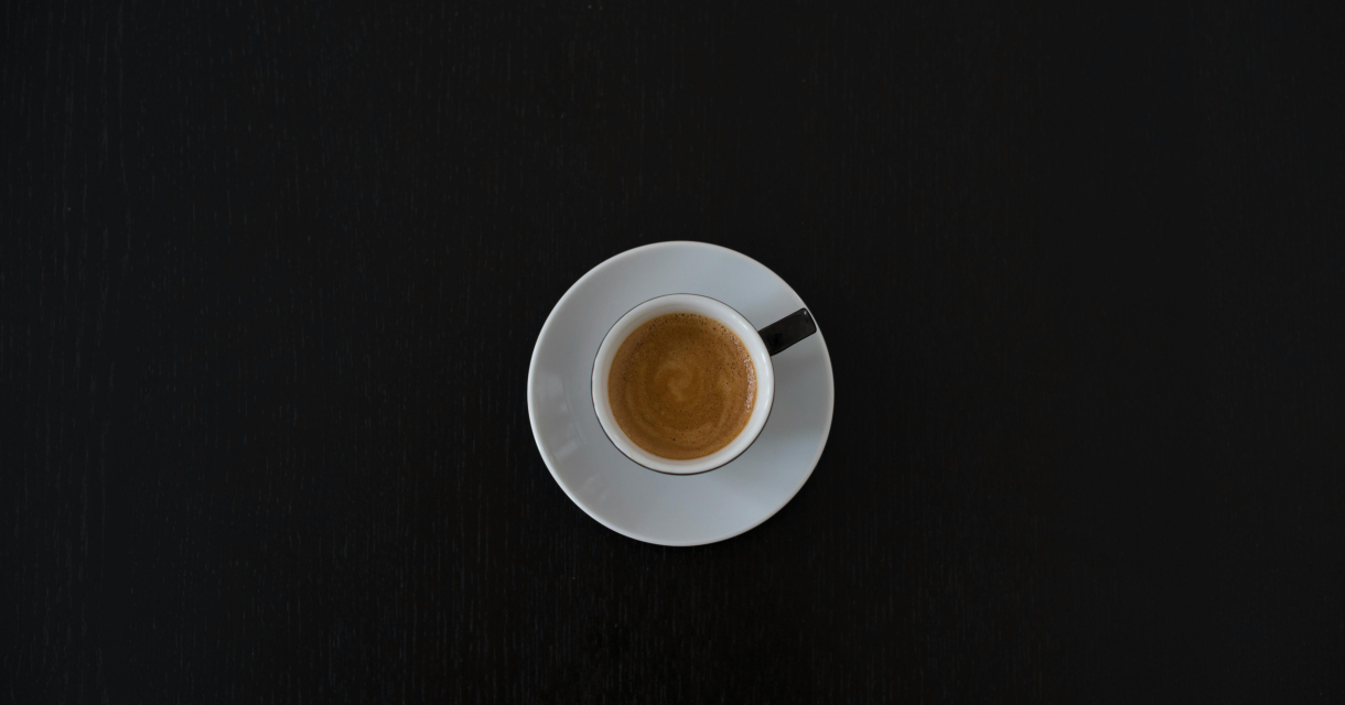 Een espresso in een witte kop op een zwarte tafel