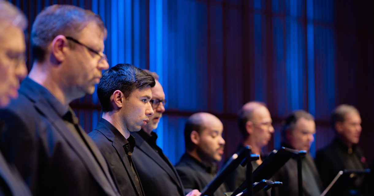 Zanggezelschap in zwarte kleding, gefocust op hun muzikale uitvoering.