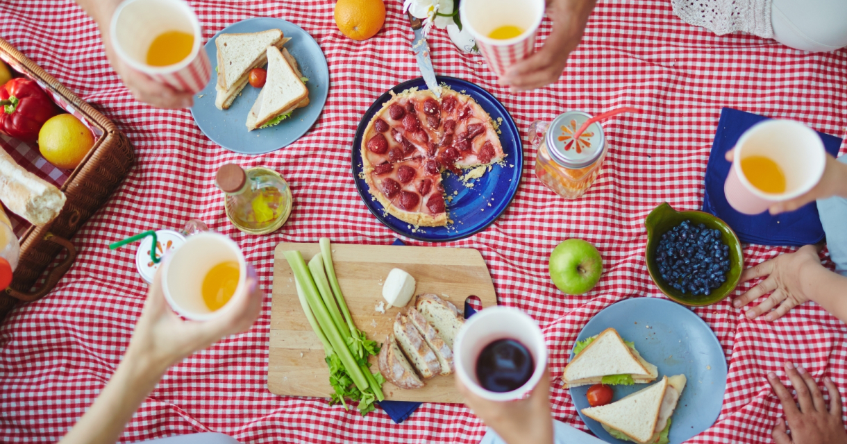 Groep mensen geniet van een picknick met eten en drinken.