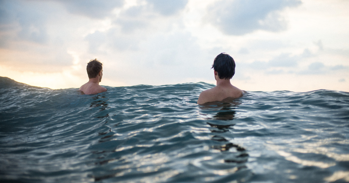 Twee mannen deinend op de golven