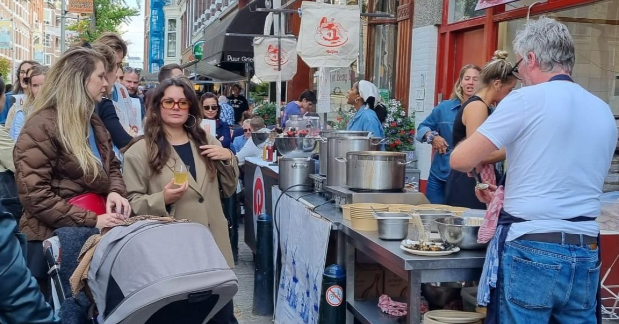 Een groep mensen wacht bij een eetkraam op de markt