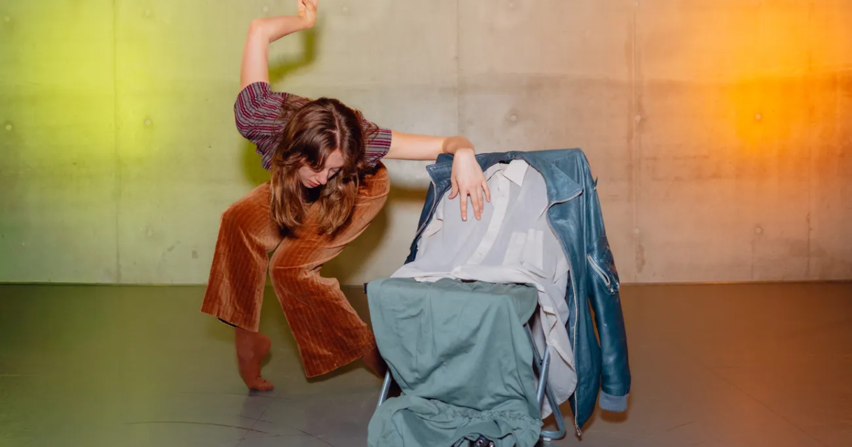 Een dansperformer in een creatieve pose met kledingstukken.