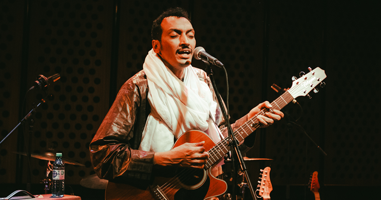 Foto van gitarist Bombino terwijl hij gitaar speelt.