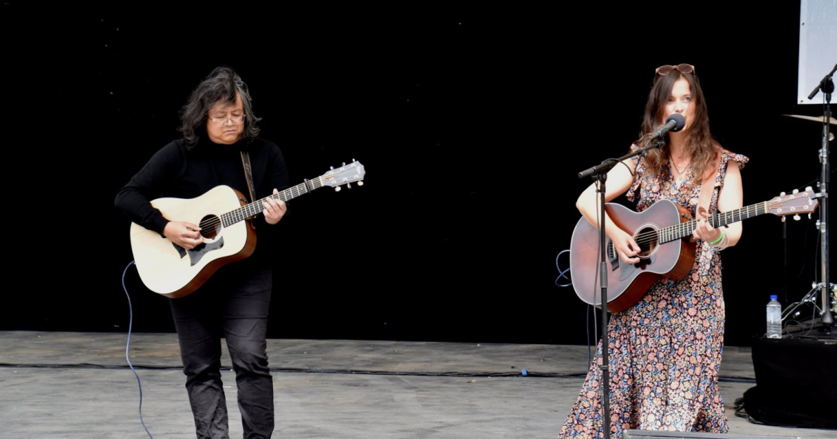 Twee muzikanten spelen gitaar en zingen op het podium.