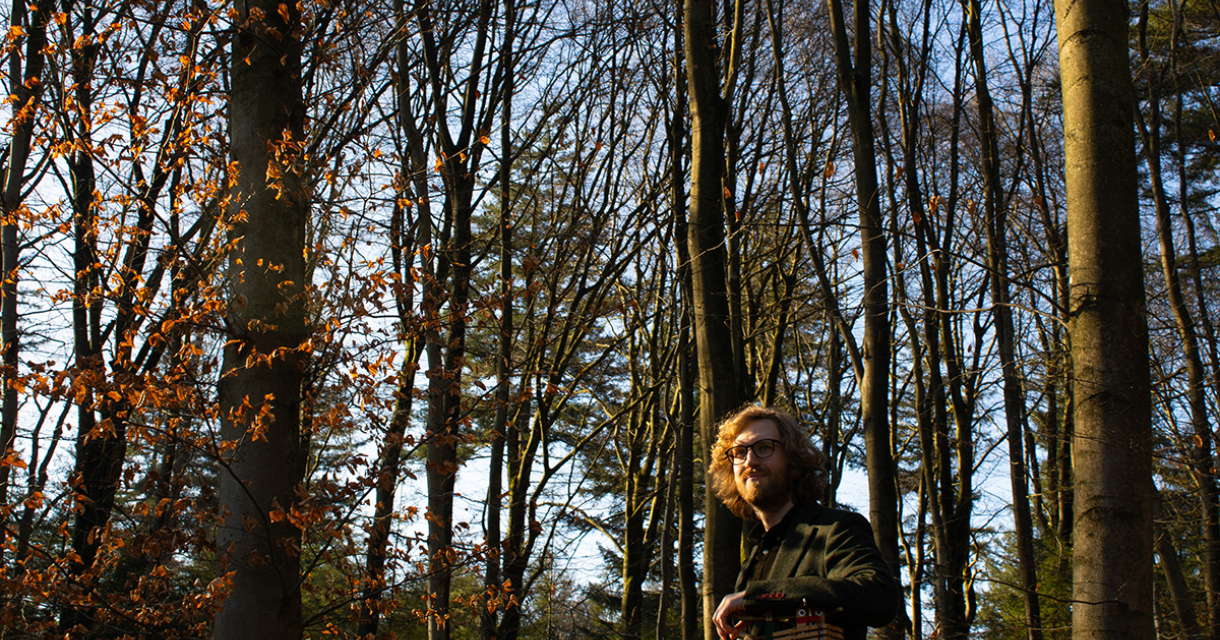 Promofoto van pianist Pianist Ben van Daal jn een bos tussen de bomen. 