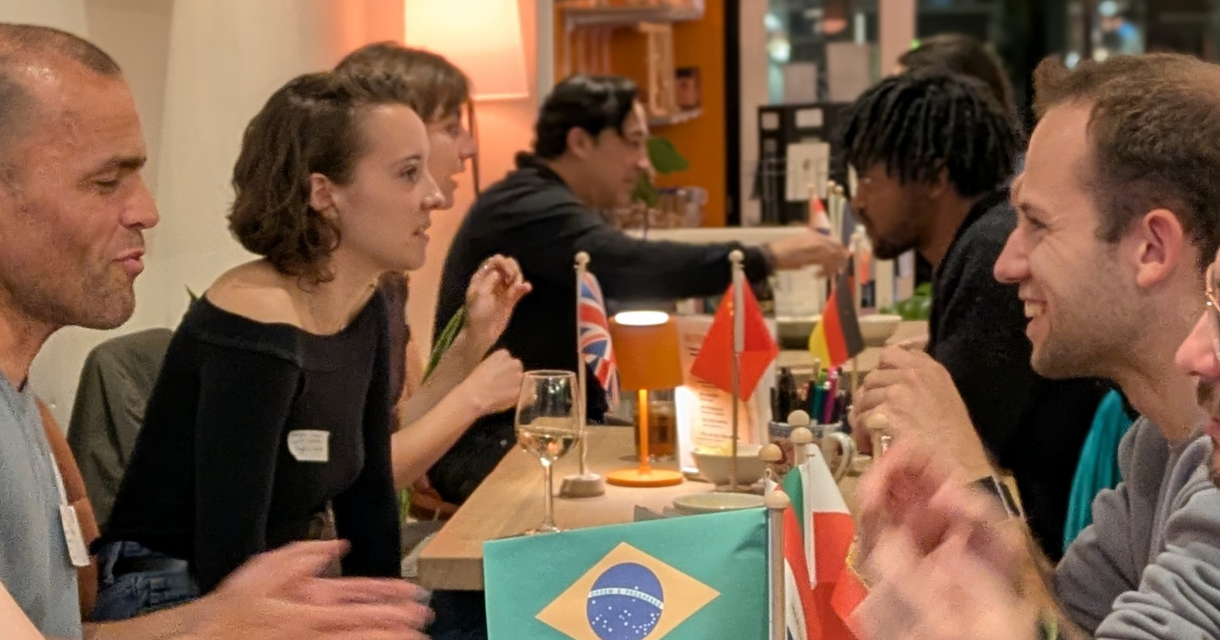 Groep mensen in gesprek met nationale vlaggen op tafel.