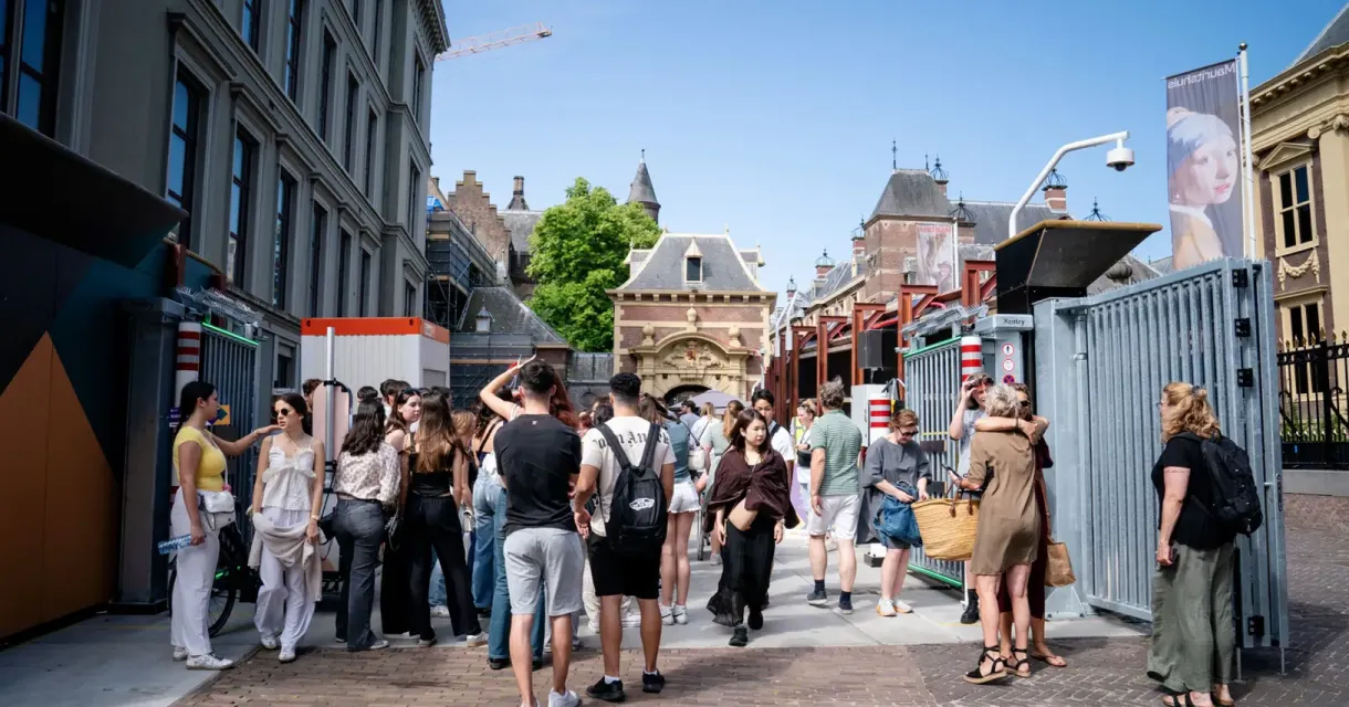 Mensen staan in een drukke straat met historische gebouwen.