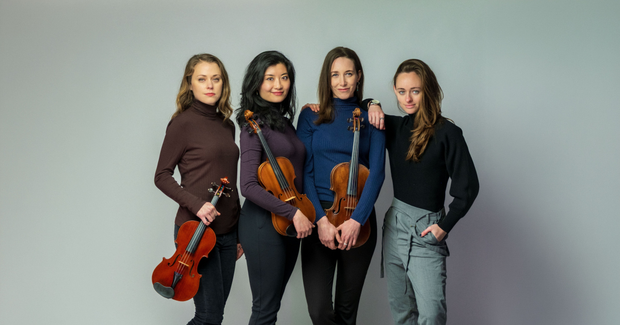 Vier vrouwen poseren met violen en een cello.