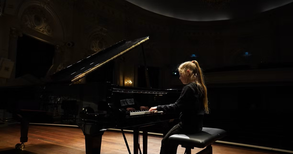 Jong meisje spelend op een klavier op een podium 