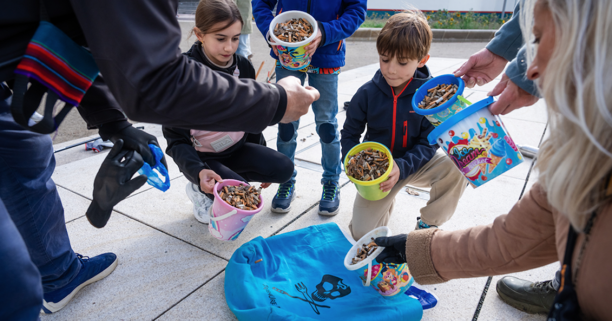Kinderen verzamelen sigarettenpeuken in emmers.