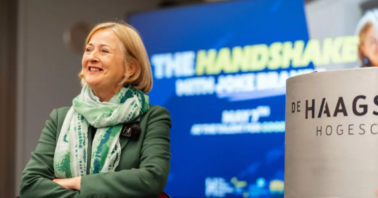 Een vrouw in een groene jas met een sjaal tijdens een evenement.