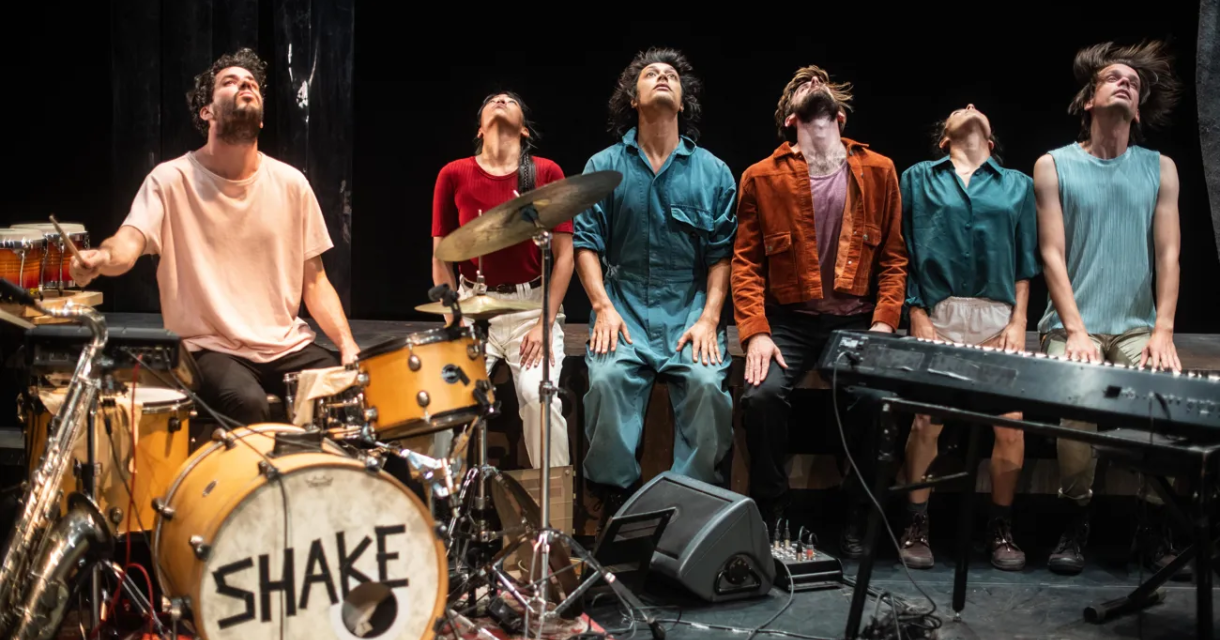 Six performers in a musical act on stage