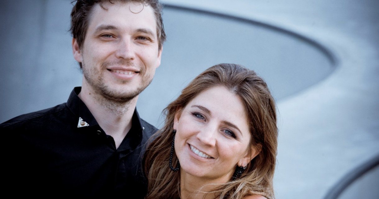 Een man en een vrouw staan dicht bij elkaar en lachen.