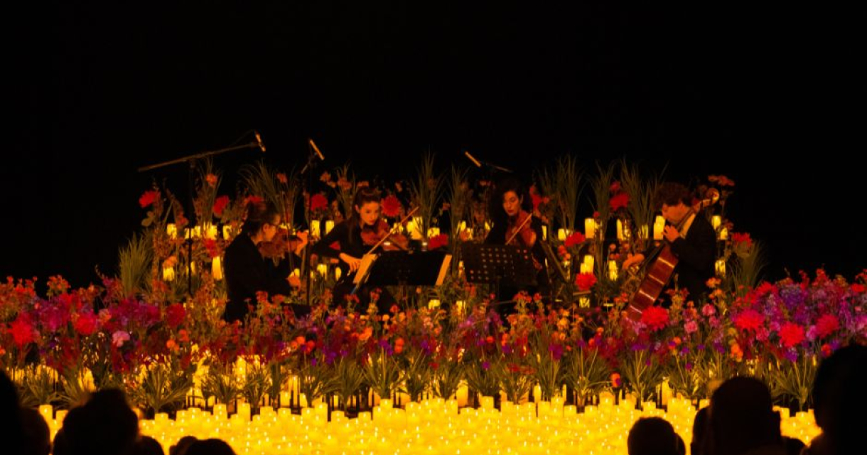 Musici spelen op een podium omgeven door bloemen en kaarsen.