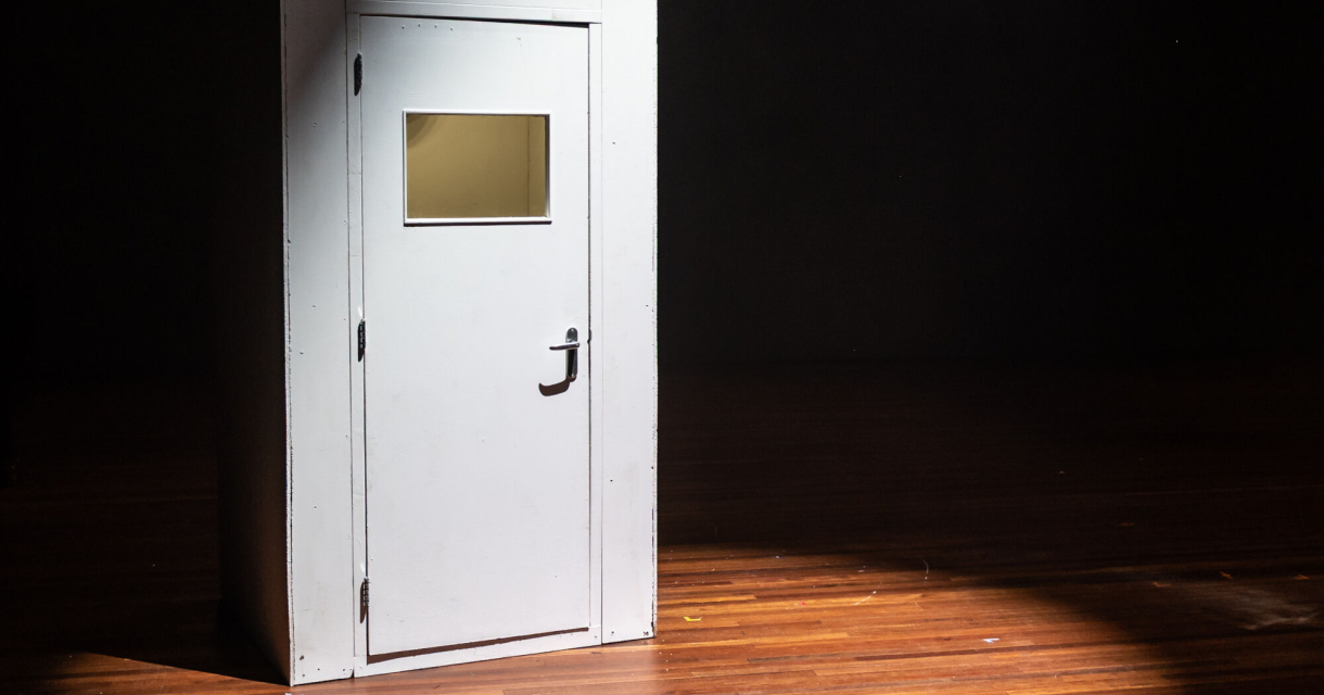 Een dichte deur op een podium in de spotlights. 