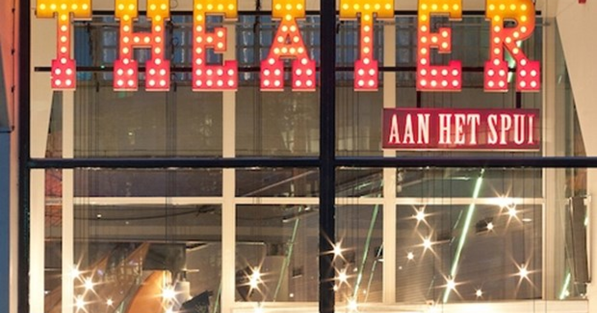 Voorkant van het Theater aan het Spui in het donker met de letters Theater in rood gele lichtjes. 