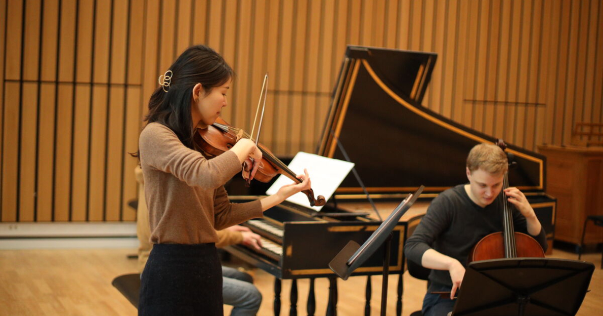 Een violiste, pianist en cellist spelen samen op een podium