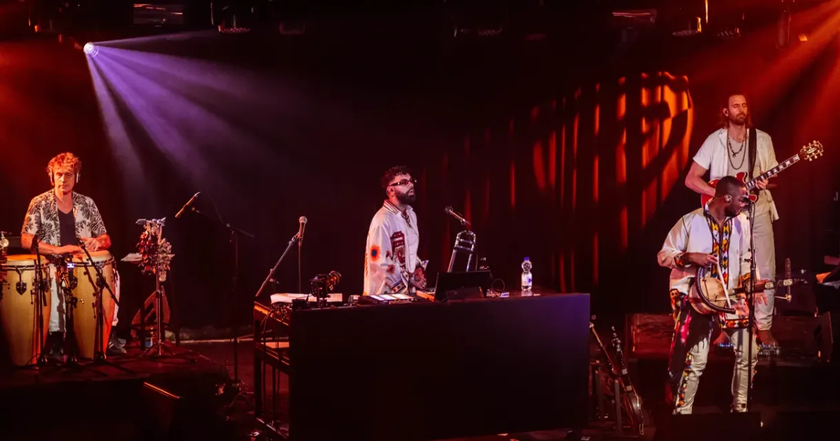 Three musicians perform live on stage with instruments.