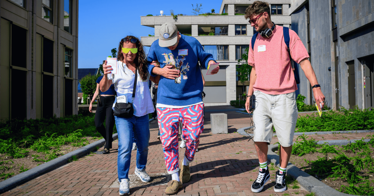 Gids begeleidt twee mensen met een visuele beperking tijdens een wandeling door Den Haag